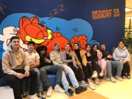 Jugendliche sitzen vor einem Wandbild mit einem schlafenden Garfield