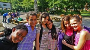 6 Mädchen stehen auf dem Schulhof und lächeln in die Kamera