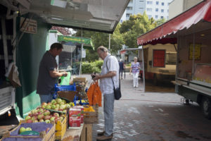 Ein Marktbesucher kauft am Obst/Gemüse-Stand ein