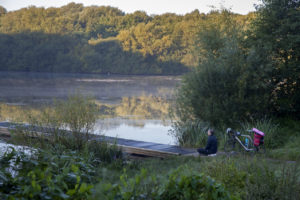 Landschaftsbild Bornpark, Helmuth-Schack-See, 1 Fahrradfahrer sitzt am Steg und meditiert